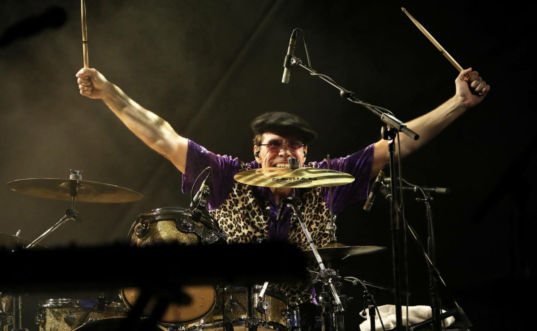 A man with his arms up playing drums