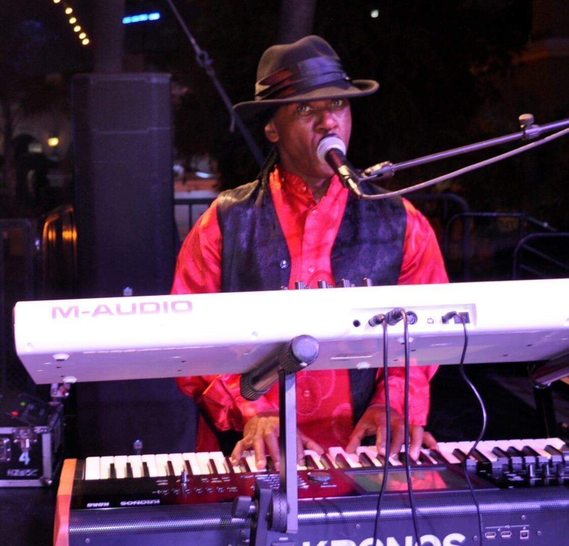 A man in red shirt playing keyboard and microphone.