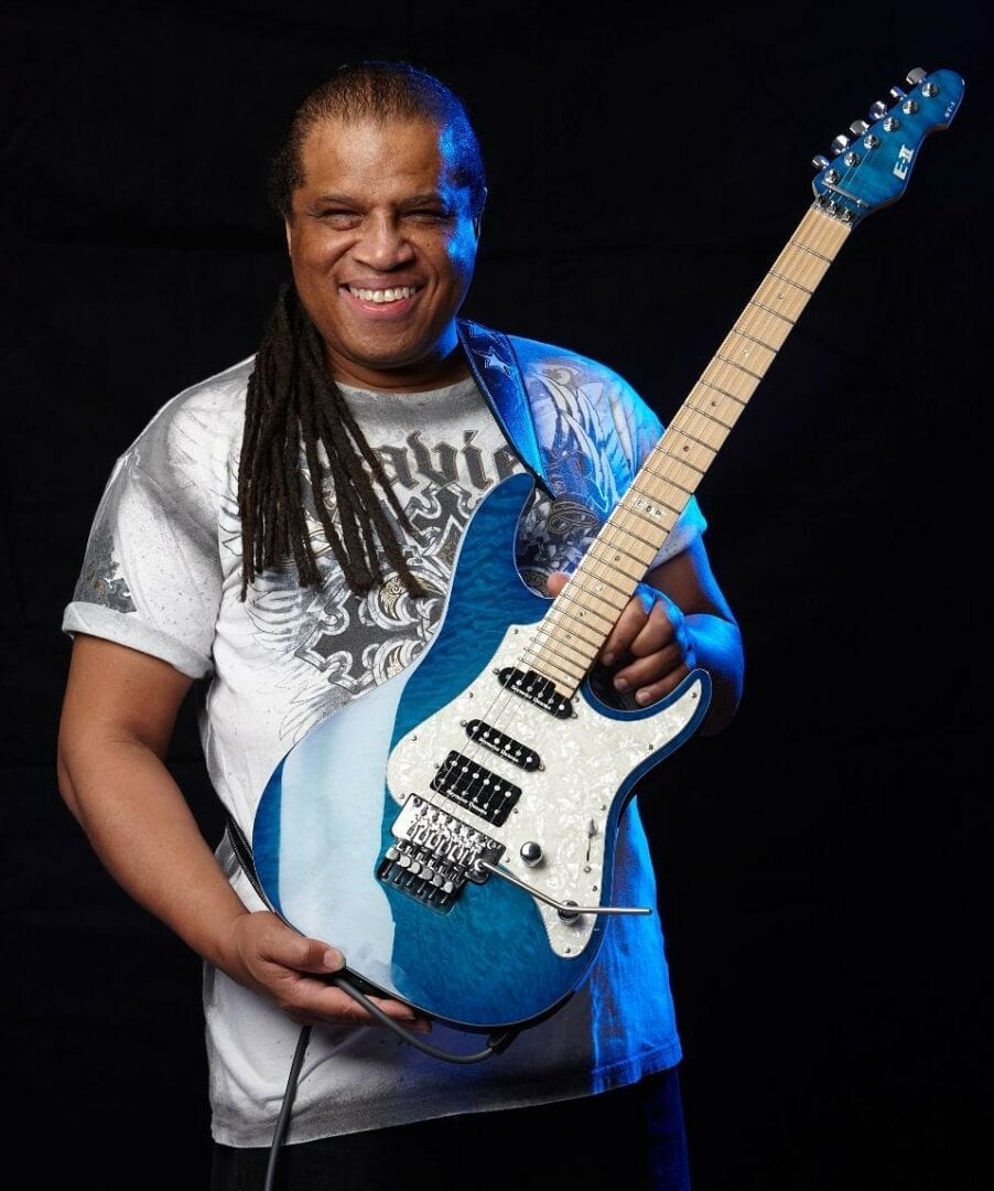 A man holding a blue guitar in front of him.