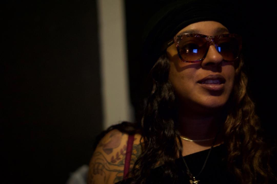 A woman with tattoos and glasses is looking at the camera.