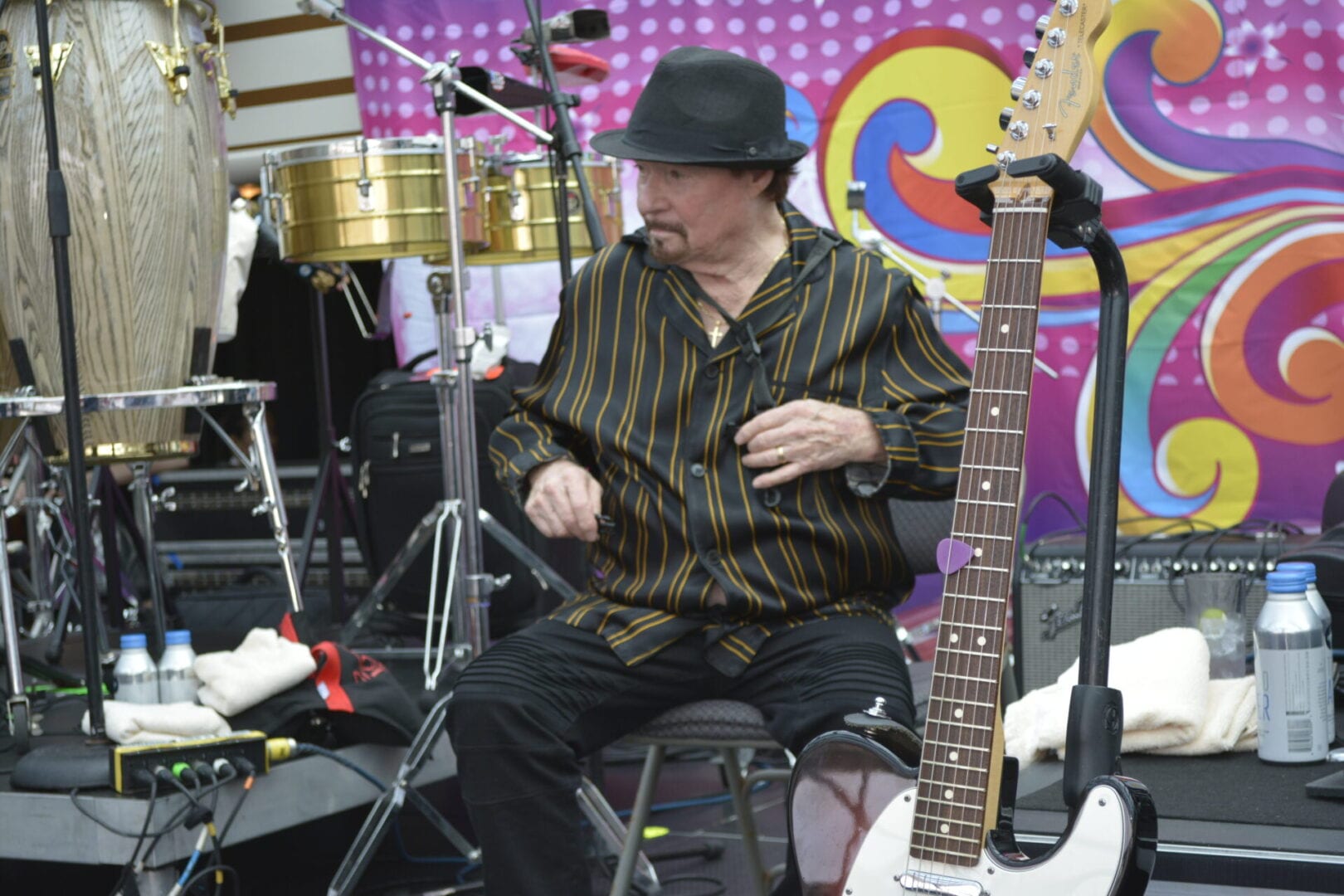 A man sitting in front of a guitar and drums.