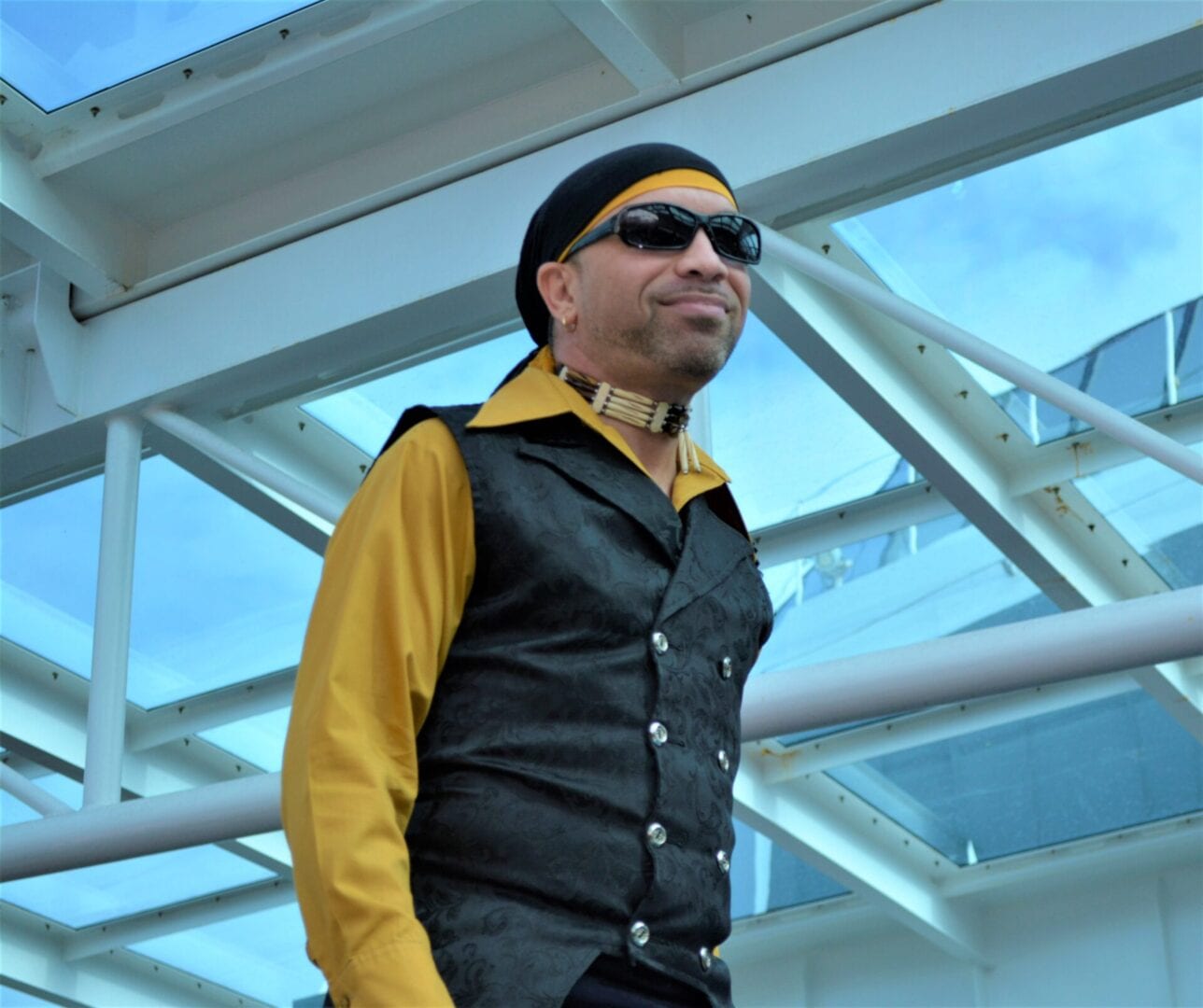 A man in black and yellow shirt standing next to a building.
